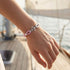 Herren Ankerarmband mit Edelstahl Anker und rosa weißem Segeltau auf einer Yacht am Meer getragen