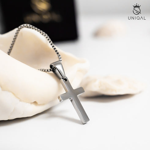 Edelstahl Kreuz Halskette auf Tischdeko mit Pflanzen und UNIQAL Verpackung