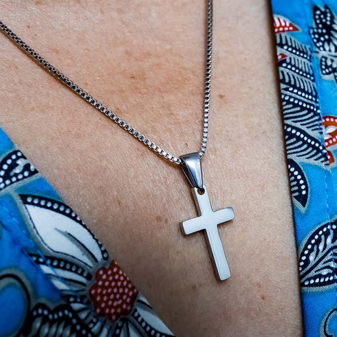 Klassische Kreuz Halskette aus Edelstahl getragen auf blauem Oberteil uniqal