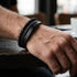 Schwarzes Herren Lederarmband mit Lava Naturstein Perlen und Edelstahl Element im modernen Casual Look getragen