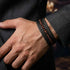 Elegantes schwarzes Herren Lederarmband mit braunen Naturstein Perlen und geflochtenem Leder zum Anzug getragen