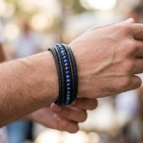 Schwarzes Herren Lederarmband mit blauen Naturstein Perlen und geflochtenem Leder am Handgelenk getragen