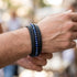 Schwarzes Herren Lederarmband mit blauen Naturstein Perlen und geflochtenem Leder am Handgelenk getragen