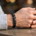 Elegantes schwarzes Herren Lederarmband mit Kreuz Motiv und schwarzem Edelstahl am Handgelenk getragen