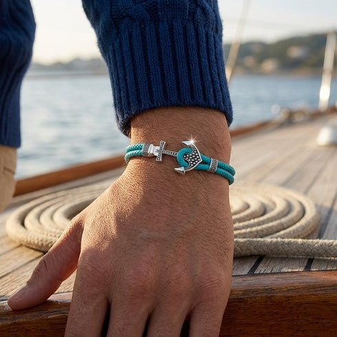 Maritimes Ankerarmband für Herren mit türkisem Seil vor dem Meer getragen