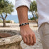 OCEAN SPIRIT Armband am Handgelenk eines Mannes auf Felsen – nautisches Lederarmband UNIQAL