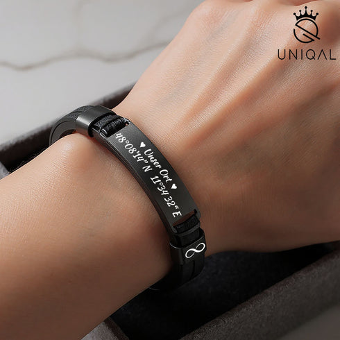 Uniqal BLACK LEGACY Gravurarmband auf Männerhand – schwarzes Echtleder & Edelstahl mit eingravierten Koordinaten des Zuhause unser Ort, Symbol für Heimat, Liebe & Erinnerung