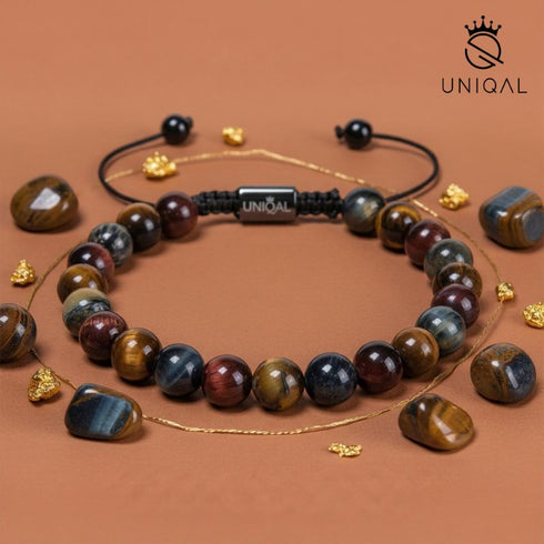 Falkenauge Armband umgeben von Natursteinen auf warmem Hintergrund in Erdtönen