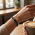 Schwarzes Schmuckaccessoire am weiblichen Arm neben Kaffeetasse, modisch kombinierbar für Alltag und Freizeit.