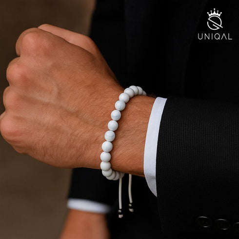 Howlith-Armband mit weißen Edelsteinperlen am männlichen Handgelenk im eleganten Anzug-Look
uniqal