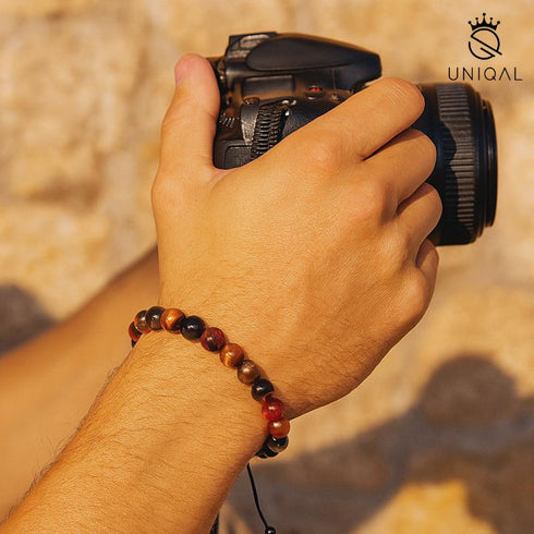 Armband aus Tigerauge und Labradorit am Handgelenk eines Mannes mit Kamera – stilvoller Herrenschmuck
