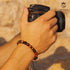 Armband aus Tigerauge und Labradorit am Handgelenk eines Mannes mit Kamera – stilvoller Herrenschmuck