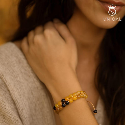 Elegantes Damenarmband aus Onyx und Honigachat am Handgelenk, fotografiert im warmen Herbstlicht – stilvolles Schmuckstück von UNIQAL für emotionale Balance und Schutz