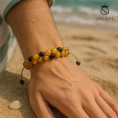 Zweireihiges Perlenarmband aus Onyx und Honigachat am Männerhandgelenk am Strand, natürliches Licht und maritimes Sommerambiente