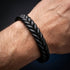 BLACK BRAID Zopfarmband in Nahaufnahme am Handgelenk eines Mannes vor dunklem Hintergrund