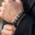 UNIQAL BLACK MAMBA Lederarmband mit gravierten Namen, Daten und Herzen am Handgelenk zu einem dunklen Sakko.