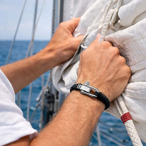 Maritimes Seilarmband Black Nautic am Handgelenk auf einer Segelyacht bei frischer Brise und gespannter Segelfläche