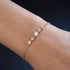 Filigranes Damenarmband ELARA 14K GOLD von UNIQAL am Handgelenk, mit fünf funkelnden Moissaniten und zarter vergoldeter Kette.