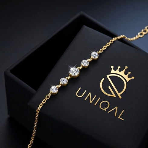 ELARA 14K GOLD Moissanitarmband über einer schwarzen UNIQAL Geschenkbox, mit feiner vergoldeter Kette und größerem Mittelstein.