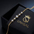ELARA 14K GOLD Moissanitarmband über einer schwarzen UNIQAL Geschenkbox, mit feiner vergoldeter Kette und größerem Mittelstein.