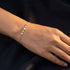 ELARA 14K GOLD von UNIQAL an einer ausgestreckten Hand vor dunklem Hintergrund, mit zarter Kette im Goldton und abgestuften Moissanit-Steinen.