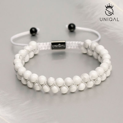 Weißes Howlith-Armband auf hellem Hintergrund mit Feder – Symbol für Ruhe & Leichtigkeit