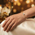 Feines vergoldetes Armband mit brillantem Mittelstein am Handgelenk in femininem Lifestyle Setting mit heller Mode.
