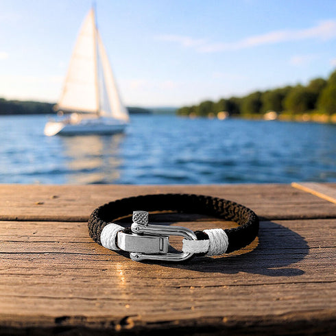 Nautisches Seilarmband QUERENCIA in Schwarz Weiß vor Küstenlandschaft und ruhigem Wasser von Uniqal Personalisieren