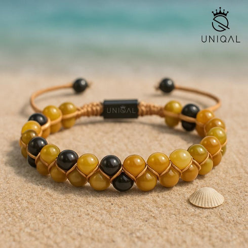 Handgemachtes Armband mit natürlichen Heilsteinen, fotografiert im Sand mit Muschel – Symbol für Balance und Erdung.