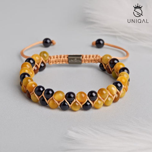 Glänzende Perlen in Gelb und Schwarz, geflochten mit hellbraunem Band – dezentes Statement für Stärke.