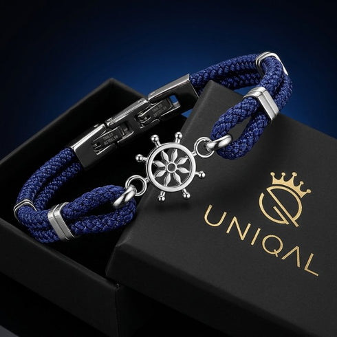 Dunkelblaues RHODOS Tauarmband mit silberfarbenem Steuerrad in einer schwarzen Geschenkbox mit goldenem UNIQAL Logo.