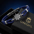 Dunkelblaues RHODOS Tauarmband mit silberfarbenem Steuerrad in einer schwarzen Geschenkbox mit goldenem UNIQAL Logo.