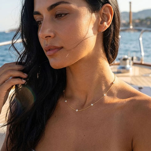 SHINE CELESTA 14K GOLD von UNIQAL, getragen auf einem Segelboot: feiner Damenschmuck im warmen Goldton mit dezenten Moissanit-Akzenten.