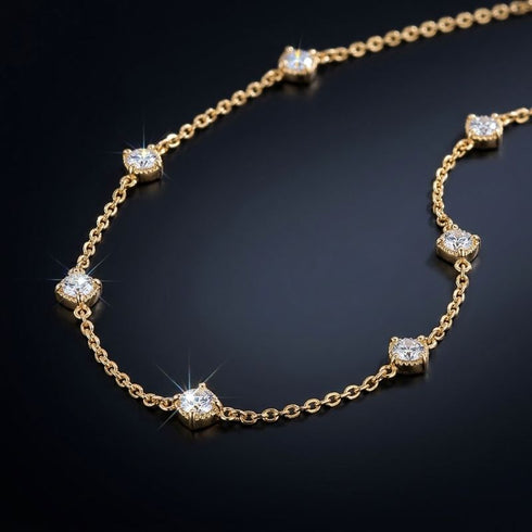 Nahaufnahme der SHINE CELESTA 14K GOLD von UNIQAL: farblose Moissanite im Rund-Brillantschliff, goldplattierte Fassungen und feine ovale Glieder.