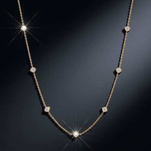 SHINE CELESTA 14K GOLD von UNIQAL als zartes Station-Collier mit sieben gleichmäßig verteilten Edelsteinen und Lichtreflexen vor dunklem Hintergrund.