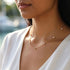 SHINE CELESTA 14K GOLD von UNIQAL zur weißen Bluse: eine zarte Edelsteinkette mit goldener Oberfläche und einzeln angeordneten Moissaniten.