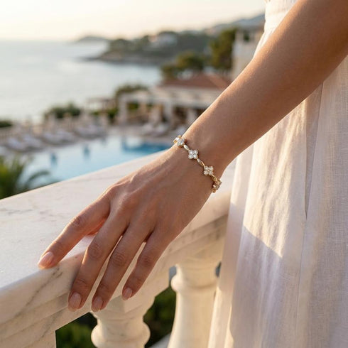 Florales Moissanit Armband mit goldener Oberfläche am Handgelenk in exklusiver Resort Kulisse mit stilvoller Eleganz.