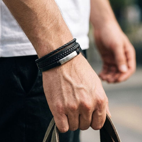 Uniqal BLACK OLIVE Armband am Handgelenk – schwarzes mehrreihiges Herrenarmband mit geflochtenen Details und silberfarbener Metallplatte für einen lässigen Outdoor-Look.