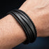 Uniqal BLACKY Herrenarmband am Handgelenk – schwarzes mehrreihiges Lederarmband mit geflochtenen Details und markanter Struktur.