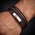 Uniqal BROWN OLIVE Armband am Handgelenk – mehrreihiges braunes Herrenarmband mit geflochtenen Details und silberfarbener Metallplatte.