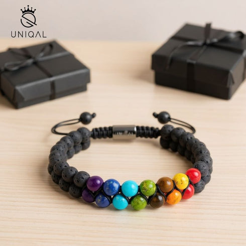Uniqal Chakra Armband aus Lavastein mit bunten Perlen für jede Chakra, handgefertigtes Geschenk zu Weihnachten auf Holztisch mit Geschenkboxen.