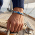 UNIQAL CORSO BLAU Edelstahl Armband am Handgelenk auf einem Boot mit blauem Steuerrad und Hämatit-Elementen