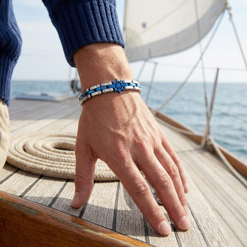 UNIQAL CORSO BLAU maritimes Armband am Handgelenk auf einer Yacht mit blauem Steuerrad und silbernen Edelstahlgliedern