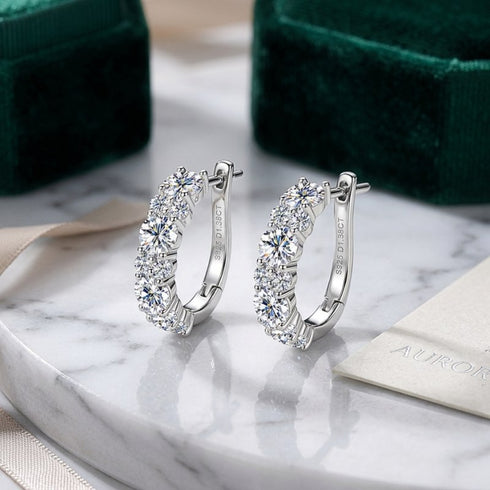 UNIQAL DIAMORA Schmuckpaar stilvoll präsentiert neben luxuriöser Verpackung auf Marmoroberfläche