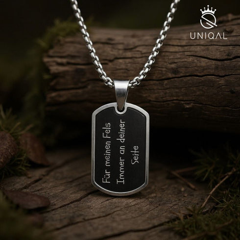 Dog Tag Halskette aus Edelstahl mit emotionaler Gravur „Für meinen Fels – Immer an deiner Seite“, fotografiert im natürlichen Outdoor Look, hochwertiger Männerschmuck von Uniqal.