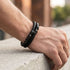 UNIQAL DOUBLE LAYER BLACK – seitliche Trageansicht des schwarzen Herrenarmbands mit doppelter Lederflechtung und Metallelementen