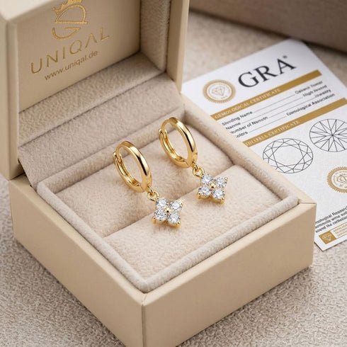 ÉCLAT 14K GOLD Moissanit-Ohrringe von UNIQAL in einer cremefarbenen Geschenkverpackung mit sichtbaren Zertifikatsunterlagen
