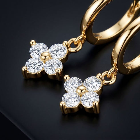 UNIQAL ÉCLAT 14K GOLD Moissanit-Ohrringe mit Kleeblatt-Motiven, als Paar schräg auf schwarzer Oberfläche arrangiert