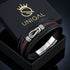 ENDLOS Infinity-Armband von UNIQAL in einer geöffneten schwarzen Geschenkbox mit goldfarbenem Logo, roten Nähten und silberfarbenen Edelstahlelementen.