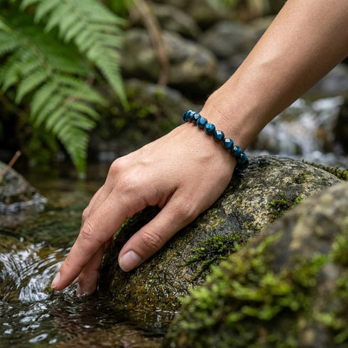 Facettiertes Falkenauge Armband auf Felsen getragen mit tiefem Farbspiel und individuell gravierbarem Makrameeverschluss